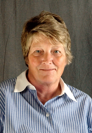 Portrait of a smiling older woman with short hair, wearing a blue striped collared shirt