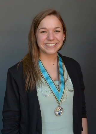 A smiling young woman in a black blazer wearing a medal on a blue ribbon
