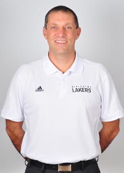 A smiling man in a white Nipissing Lakers polo shirt with his arms behind his back