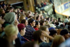 A crowd of spectators watching a game from the stands, many looking intently in the same direction