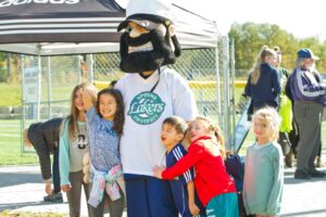 The Lakers pirate mascot posing with five smiling children at an outdoor event