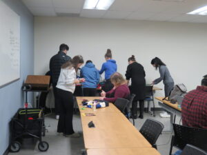 A group of people working on crafts around a long table in a classroom