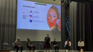 Panelists seated on a stage in front of a projection screen reading 'Resilient Inuk' with social media handles and 'No More Stolen Sisters'