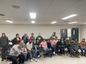 Students and staff sitting and standing together in a classroom for a group photo