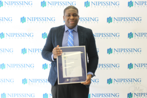 Guests and award recipients at the Dave Marshall Leadership Awards reception, posing in front of a Nipissing University backdrop
