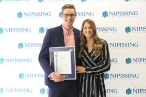 Guests and award recipients at the Dave Marshall Leadership Awards reception, posing in front of a Nipissing University backdrop