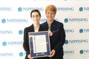 Guests and award recipients at the Dave Marshall Leadership Awards reception, posing in front of a Nipissing University backdrop
