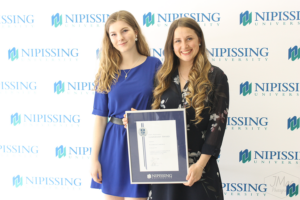 Guests and award recipients at the Dave Marshall Leadership Awards reception, posing in front of a Nipissing University backdrop