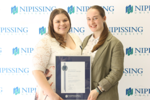 Guests and award recipients at the Dave Marshall Leadership Awards reception, posing in front of a Nipissing University backdrop
