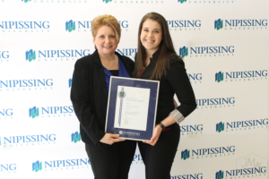 Guests and award recipients at the Dave Marshall Leadership Awards reception, posing in front of a Nipissing University backdrop